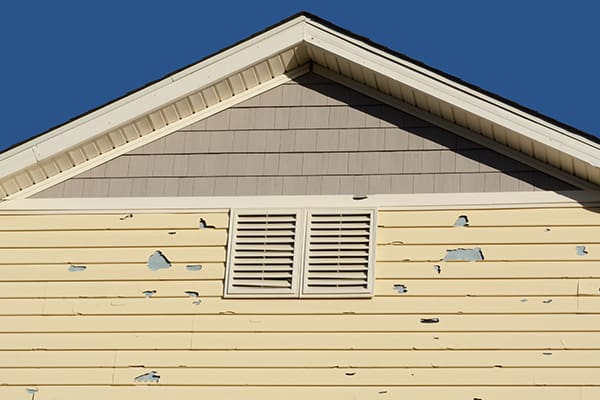 a home with yellow siding in need of repairs