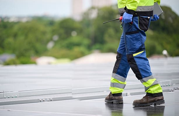 Worker holding a toolbox and inspecting the solar panel on rooftop
